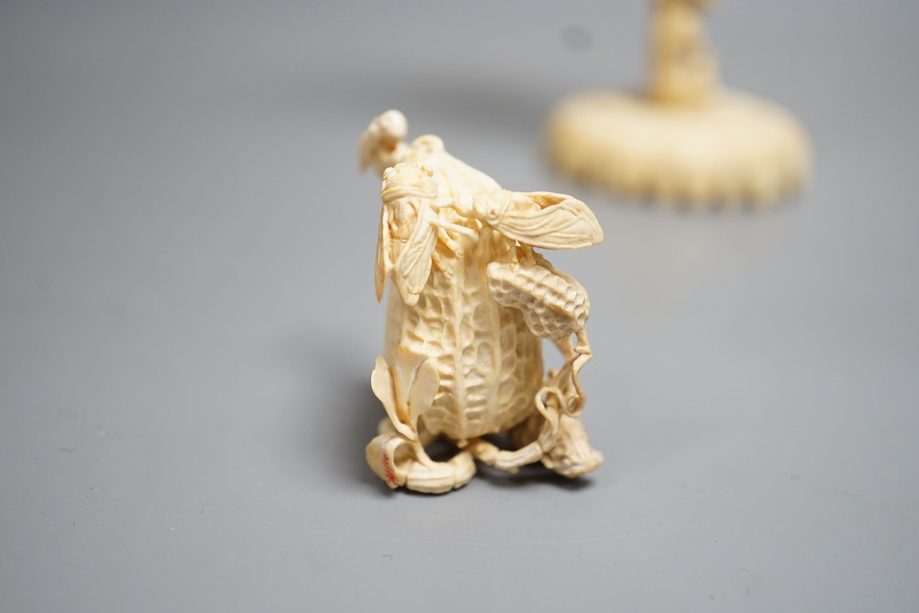 A Chinese ivory concentric puzzle ball and stand, two Chinese ivory snuff bottles and stoppers, modelled as a leaping carp and as cicadas on a nut, early 20th century